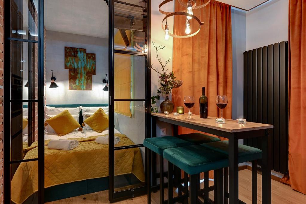 a room with a bed and a table with wine glasses at DOKI Living & Foodhall by Downtown Apartments in Gdańsk