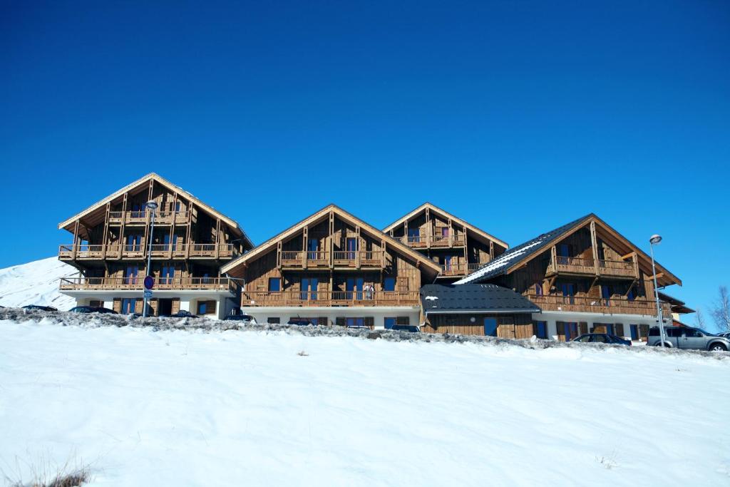 a large wooden building in the snow in front at Résidence Néméa Les Chalets Des Cîmes in La Toussuire