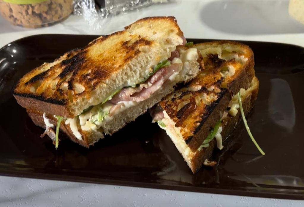 a sandwich is cut in half on a black plate at AUBERGE et BISTRO NAMASTÉ in Lachute