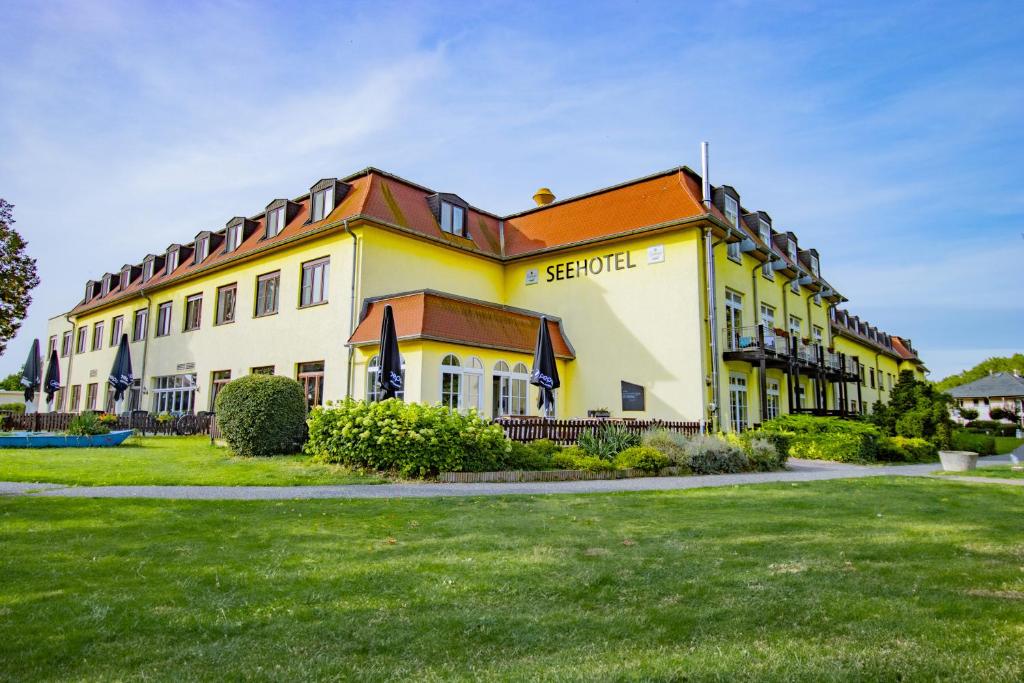 ein großes gelbes Gebäude mit orangefarbenem Dach in der Unterkunft Seehotel Brandenburg an der Havel in Brielow