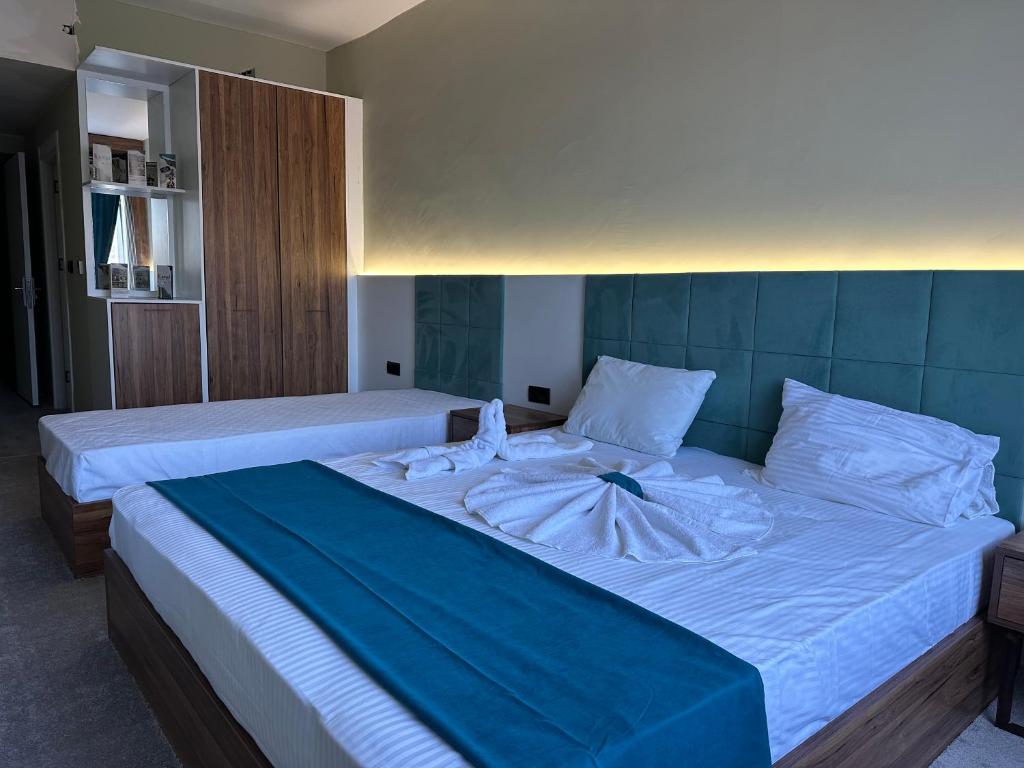 a large bed with white sheets and a blue blanket at Kançul Hotel Taştepeler in Urfa