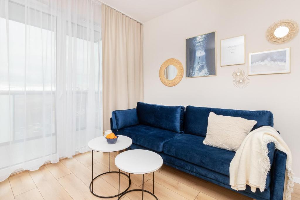 Apartment Sucha Nowa Letnica by Renters في غدانسك: غرفة معيشة مع أريكة زرقاء وطاولة