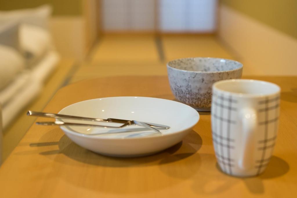 a bowl and two cups sitting on a table at Guesthouse ZenNichi in Kyoto