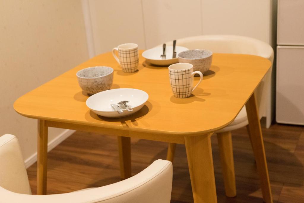 a wooden table with bowls and cups on it at Guesthouse ZenNichi in Kyoto