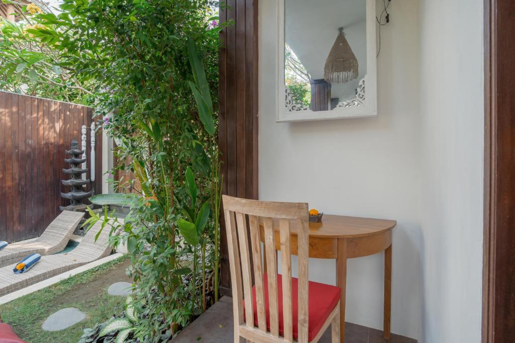 une table et une chaise dans une pièce ornée de plantes dans l'établissement Villa Balika 2, à Canggu
