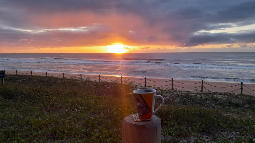 eine Tasse Kaffee auf einem Posten in der Nähe des Ozeans in der Unterkunft Villa Tartarugas 2 - Casa Luxo e Conforto - 50m da Praia de Guriri in São Mateus