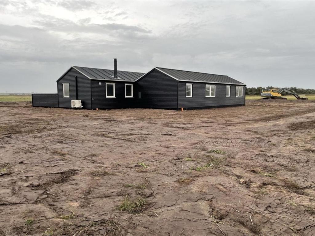 una casa negra sentada en la cima de un campo de tierra en Holiday Home Ivar - 300m from the sea in Western Jutland by Interhome, en Harboør