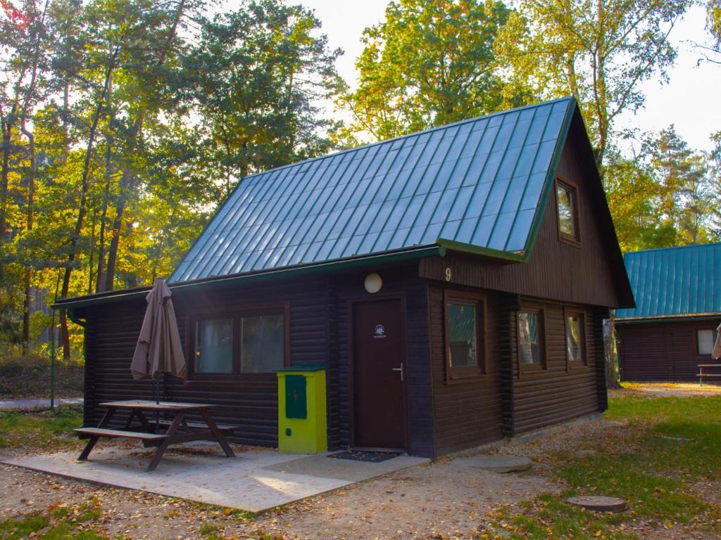 a small cabin with a picnic table and a blue roof at Holiday Home Kemp Stříbrný rybník-9 by Interhome in Hradec Králové