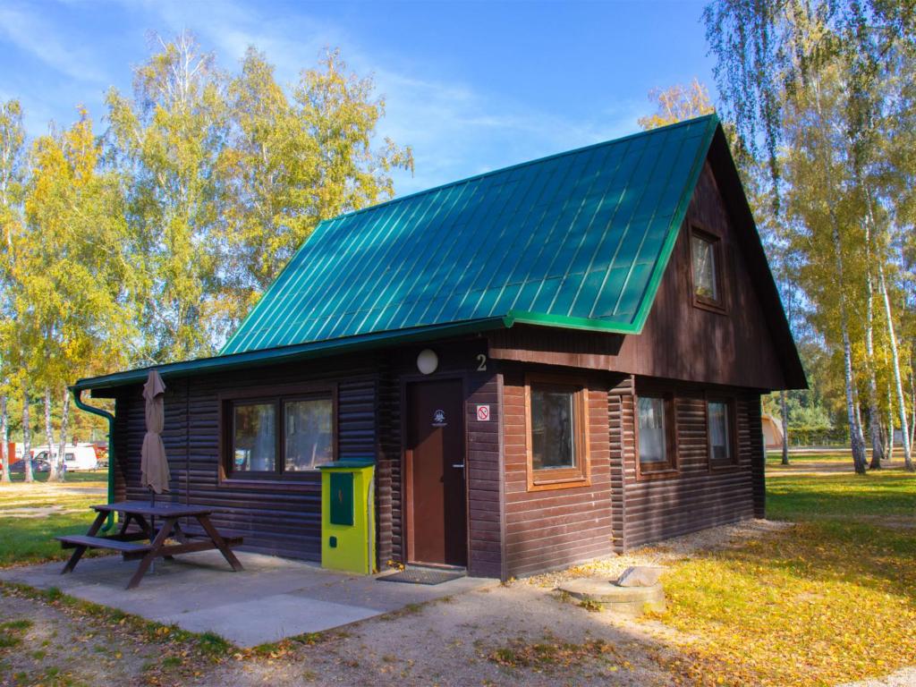 een kleine hut met een groen dak en een picknicktafel bij Holiday Home Kemp Stříbrný rybník-2 by Interhome in Hradec Králové