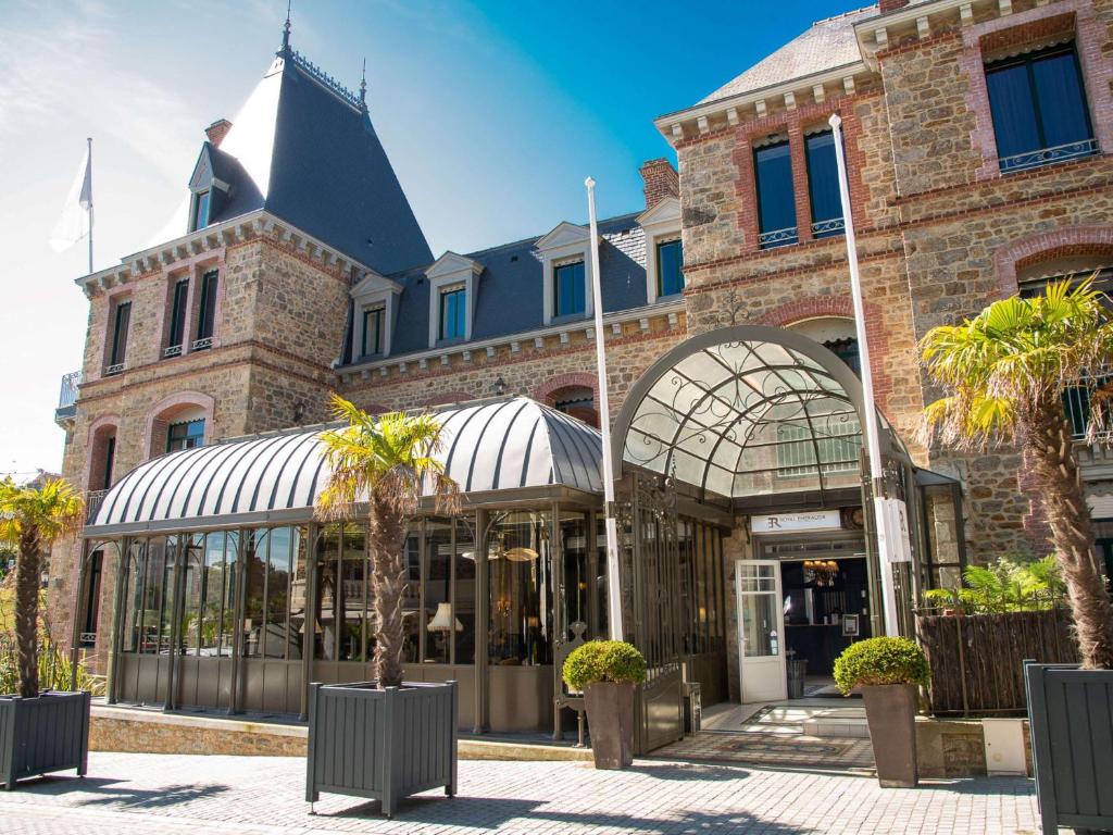 un bâtiment avec des palmiers en face de celui-ci dans l'établissement Royal Emeraude Dinard - MGallery, à Dinard