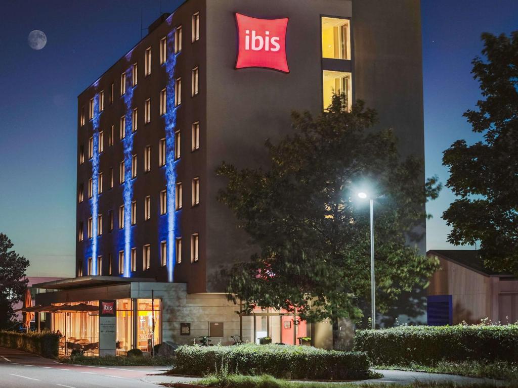 un hôtel avec un panneau sur le côté d'un bâtiment dans l'établissement ibis Hotel Friedrichshafen Airport Messe, à Friedrichshafen