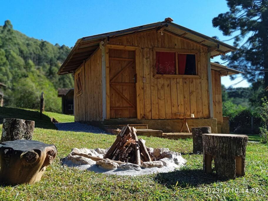una pequeña cabaña de madera con una chimenea frente a ella en Rancho Toa-toa próximo a Gonçalves MG en Sapucaí-Mirim