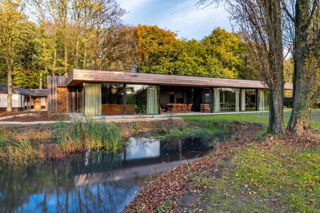une maison avec un étang en face de celle-ci dans l'établissement Equilodge 't Blommeke - Reconnect with nature, à Bruges