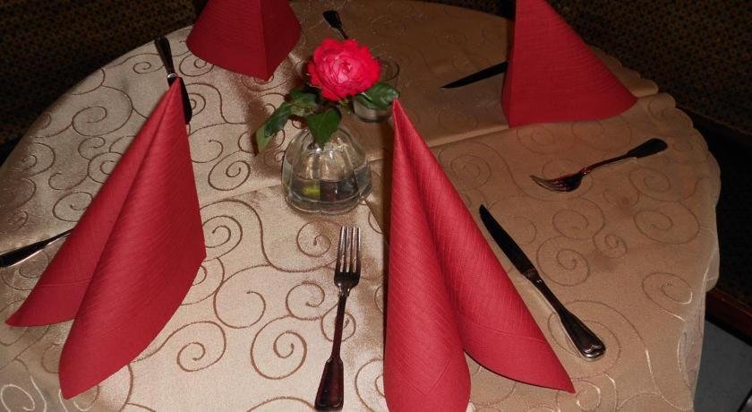 a table with red napkins and a vase with a rose at Hotel Specht in Witten