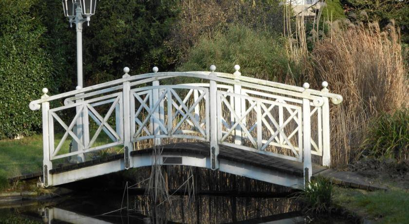 a white bridge over the water in a park at Hotel Specht in Witten