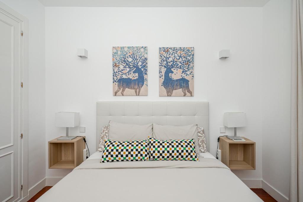 a bedroom with a white bed with two paintings on the wall at Céntrico Plaza España - Gran Vía II in Madrid