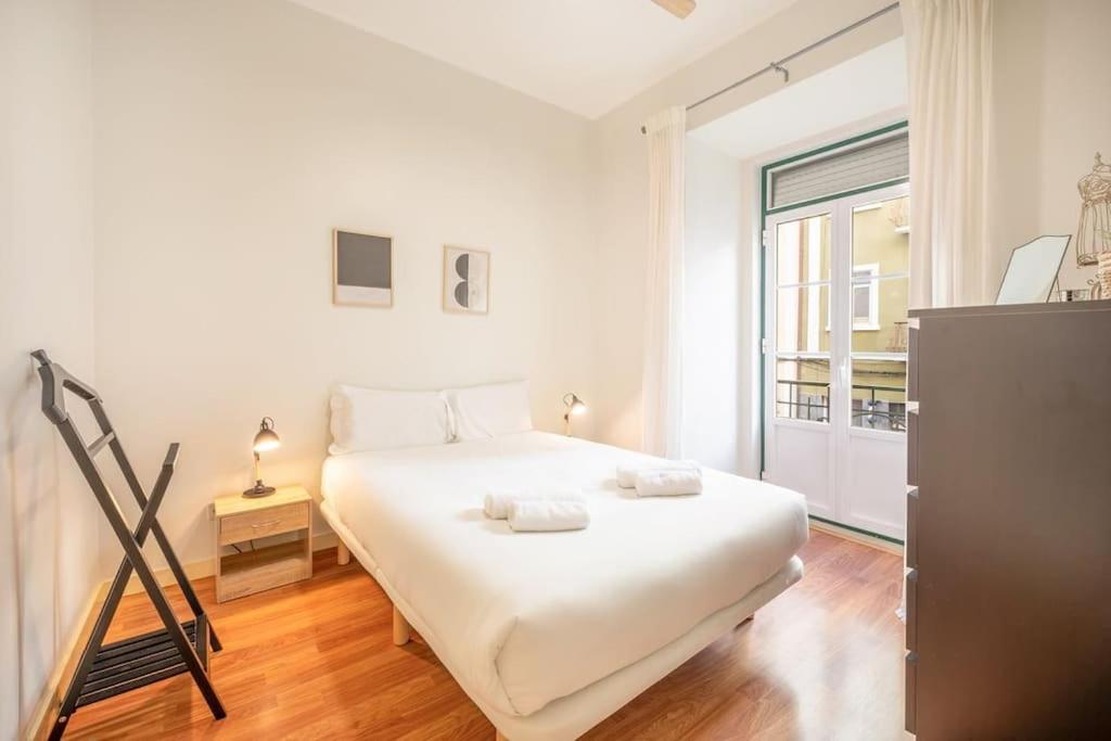 ein weißes Schlafzimmer mit einem Bett und einem Fenster in der Unterkunft GuestReady - Spring break in Lisbon in Lissabon