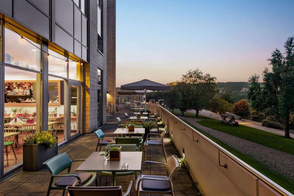 an outdoor patio with tables and chairs on a building at Vienna House Easy by Wyndham Wuppertal in Wuppertal