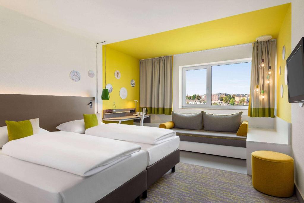 pokój hotelowy z 2 łóżkami i kanapą w obiekcie Vienna House Easy by Wyndham Wuppertal w mieście Wuppertal