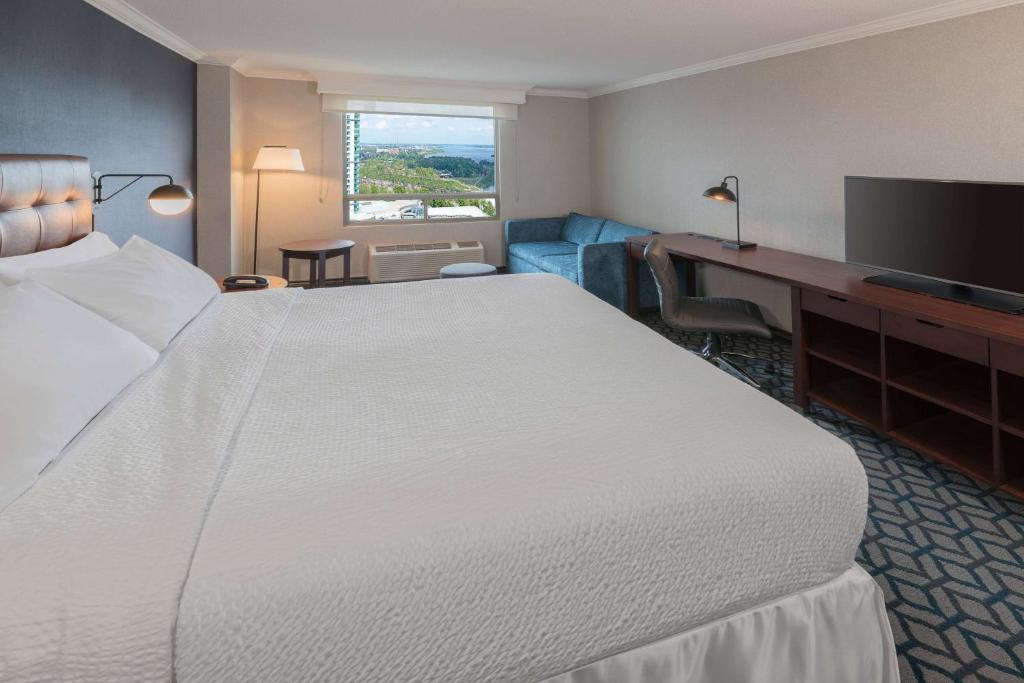 a hotel room with a large bed and a desk at Wyndham Fallsview Hotel in Niagara Falls
