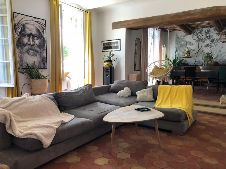 uma sala de estar com um sofá e uma mesa em Maison de village avec 2 jardins em Pernes-les-Fontaines