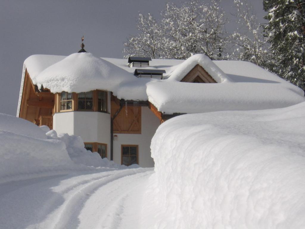 ein schneebedecktes Haus mit einem Schneehaufen in der Unterkunft Kellnerhof in Welschnofen
