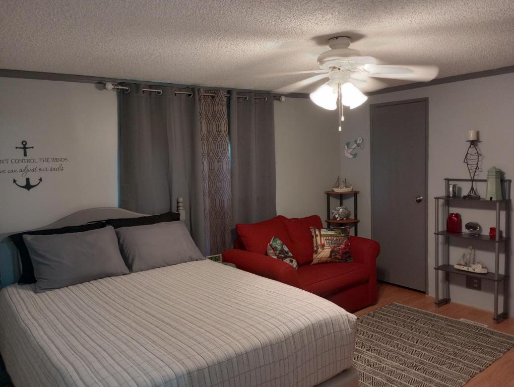 a bedroom with a bed and a red chair at Overlook Lakehouse on Chippewa Lake Close to Haymarsh State Game Area and Ferris State College in Barryton