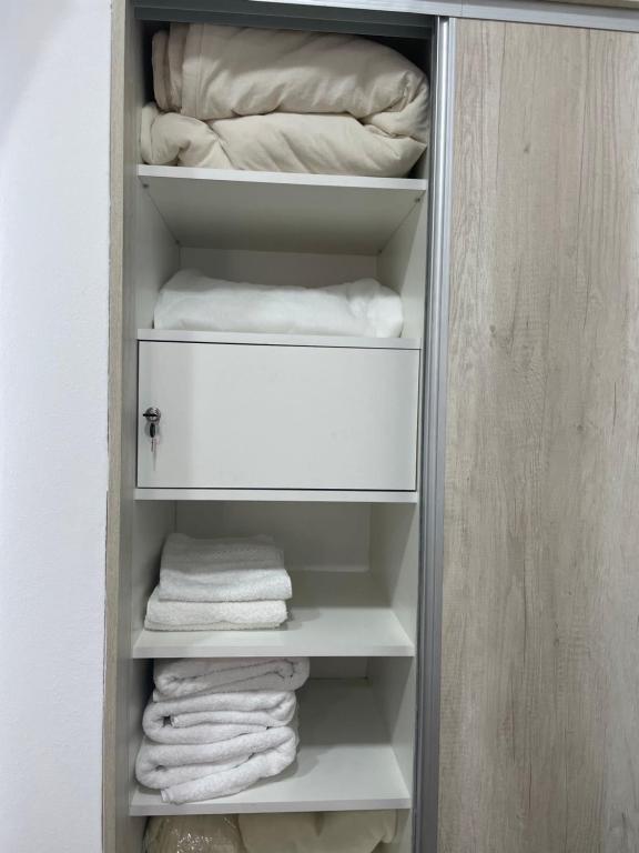 un armario con toallas blancas en los estantes en AIKA Monoambientes en Salta