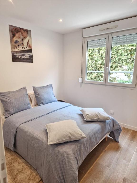 - une chambre avec un lit doté de draps bleus et 2 fenêtres dans l'établissement Spacieux et lumineux Appartement, à Aulnay-sous-Bois