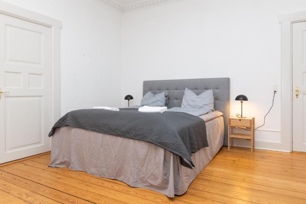 ein weißes Schlafzimmer mit einem Bett mit einer grauen Decke in der Unterkunft Århus bedst placerede lejlighed & udsigt in Arhus