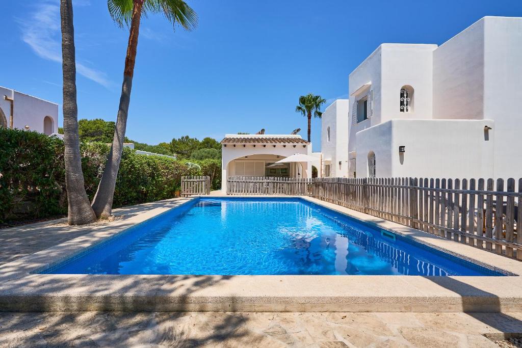 a swimming pool in front of a house at Villa Acebuche in Cala d´Or