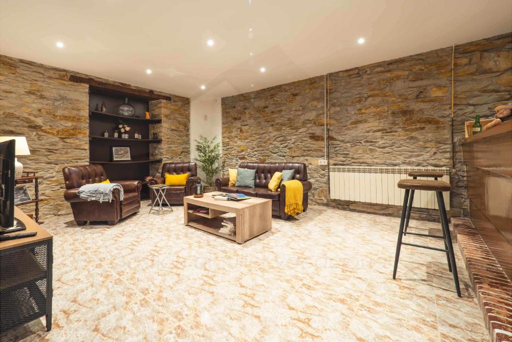 ein Wohnzimmer mit Ledermöbeln und einer Steinmauer in der Unterkunft Casa Piñera Cudillero 