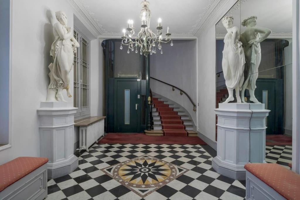 un couloir avec un lustre et un escalier orné de statues dans l'établissement AmazingApartment #GalleriesLafayette #Madeleine#AC, à Paris