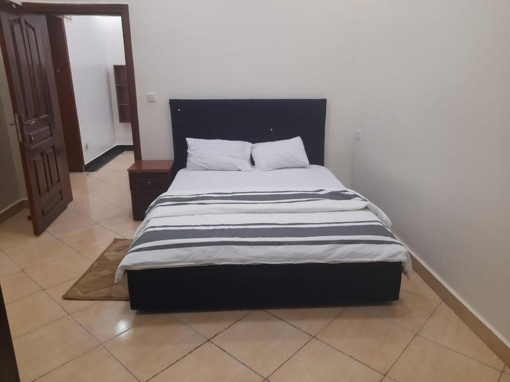 Freedom Homes Kigali في كيغالي: سرير مع لحاف مخطط اسود وبيض في غرفة