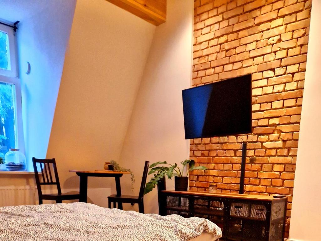 a bedroom with a tv on a brick wall at Casa Mama c entrum in Poznań