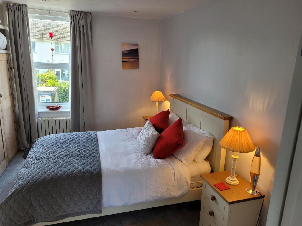 a bedroom with a bed with red pillows and a window at LITTLE HAVEN 1 Bedroom House sought after area in Topsham