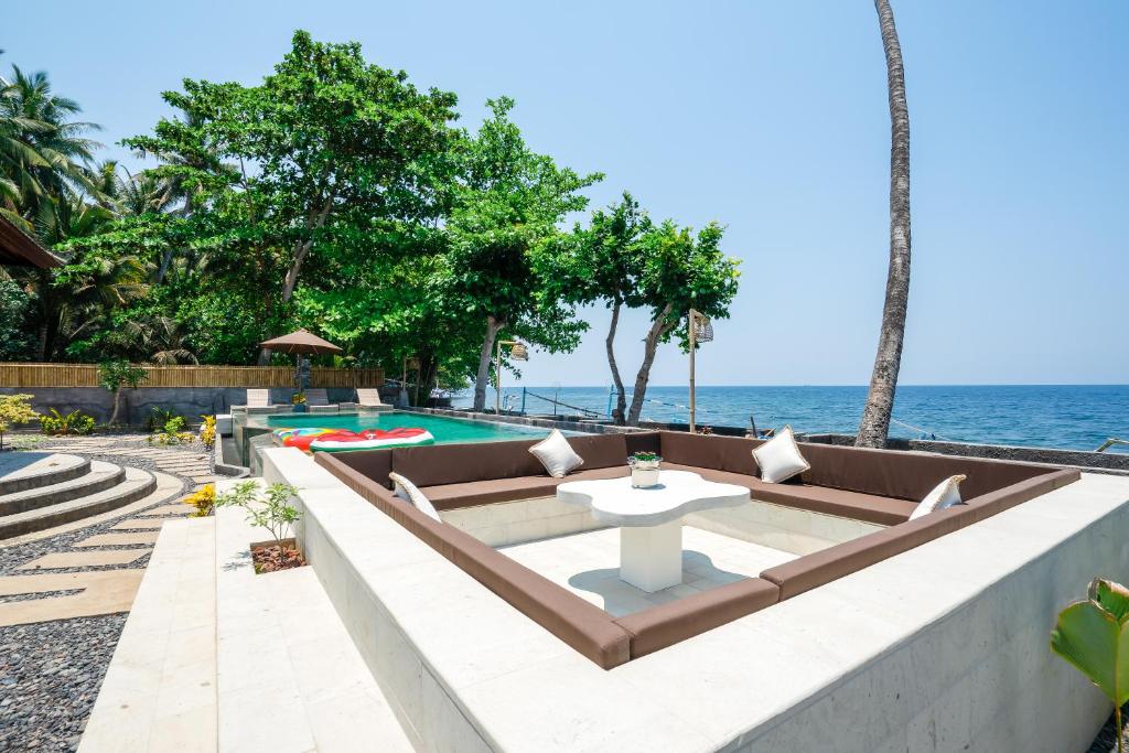un patio al aire libre con piscina y océano en Bali Taoka Beach Villa, en Singaraja