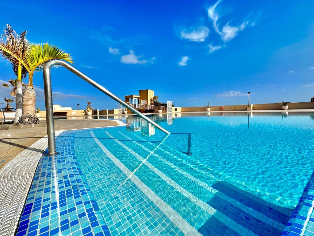 una piscina con una palmera en un edificio en Apartamento Vista Faro en Poris de Abona