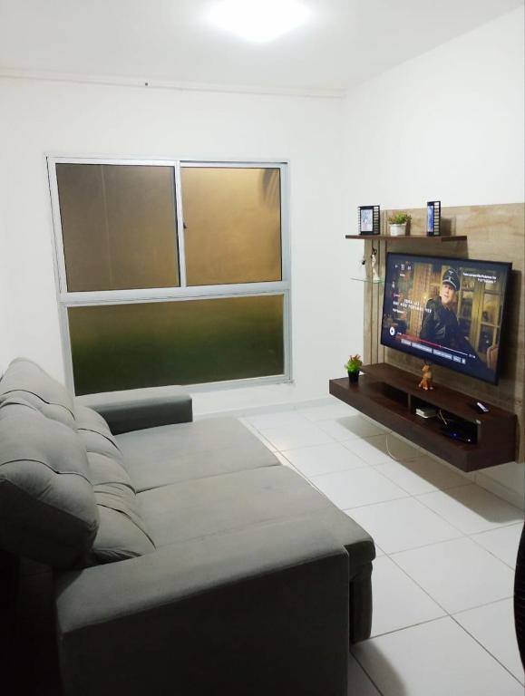 uma sala de estar com um sofá e uma televisão de ecrã plano em Apê da Mel - Recife PE no Recife