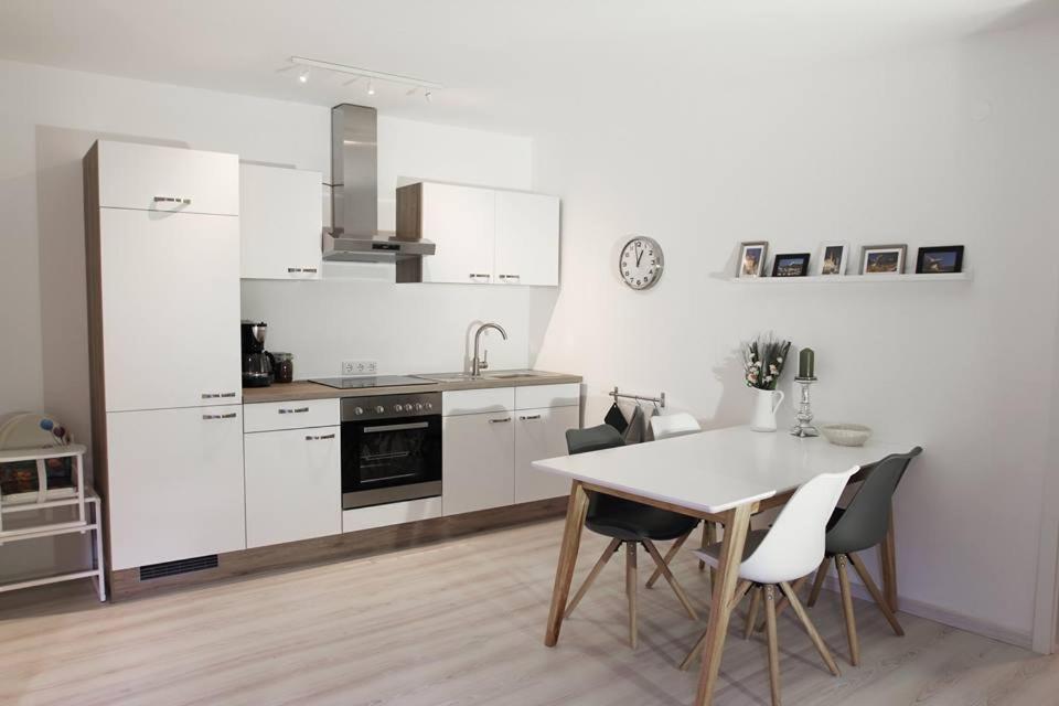 eine Küche mit weißen Schränken sowie einem Tisch und Stühlen in der Unterkunft Ferienwohnung 1 ANNA IFF in Würzburg