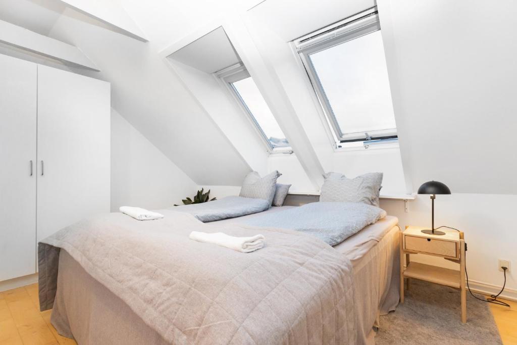 a bedroom with two beds and two windows at Centralt Byliv - 2 Soveværelser med plads til 6 in Aarhus