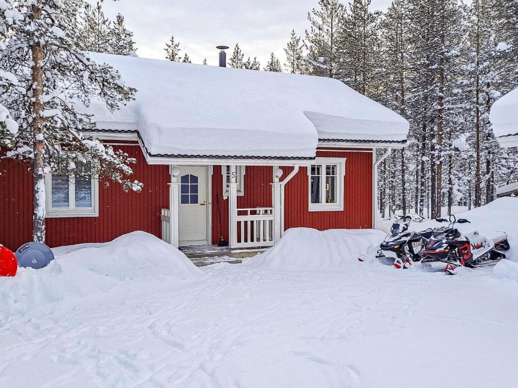una casa roja con una moto estacionada en la nieve en Holiday Home Elnan tupa by Interhome en Ylläs