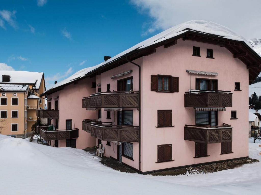 a pink building with wooden balconies in the snow at Apartment Haus Sunneschy Whg- 301 by Interhome in Parpan