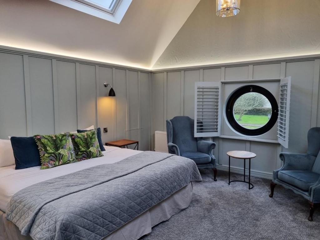 a bedroom with a bed and two chairs and a window at Killaloe Hotel & Spa in Killaloe