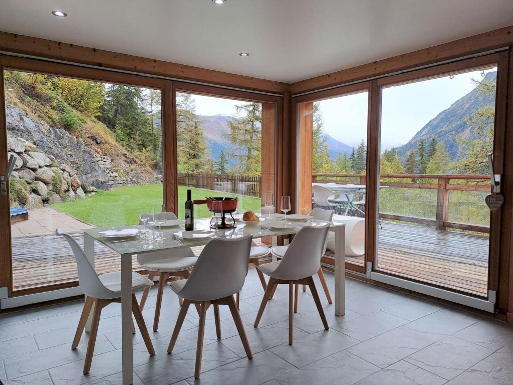 a dining room with a table and chairs and windows at Apartment L'Etoile du Matin 1er by Interhome in Champex