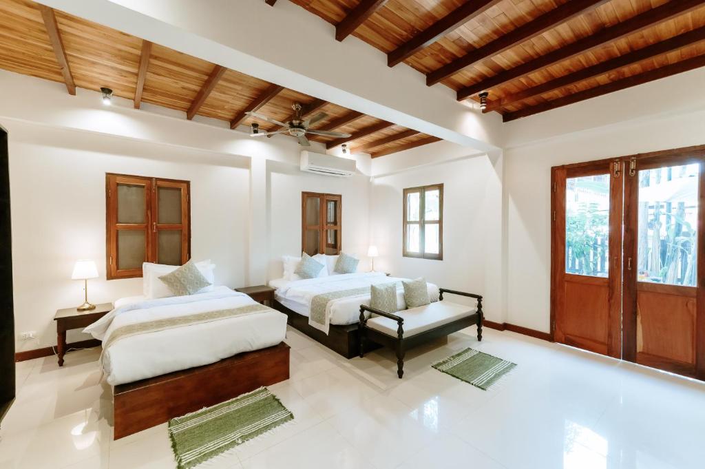 a bedroom with two beds and a couch at Maison Barn Laos in Luang Prabang