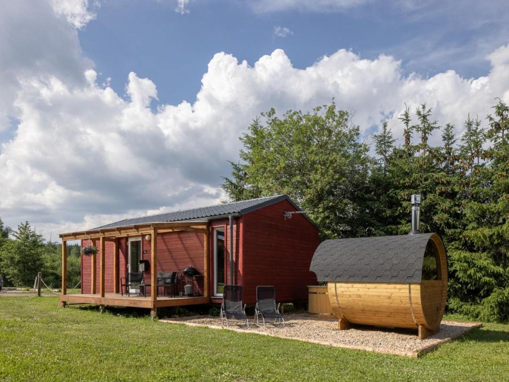 una pequeña casa roja con un barril en el césped en Holiday Home Pod Liščím Kopcem by Interhome, en Horní Branná