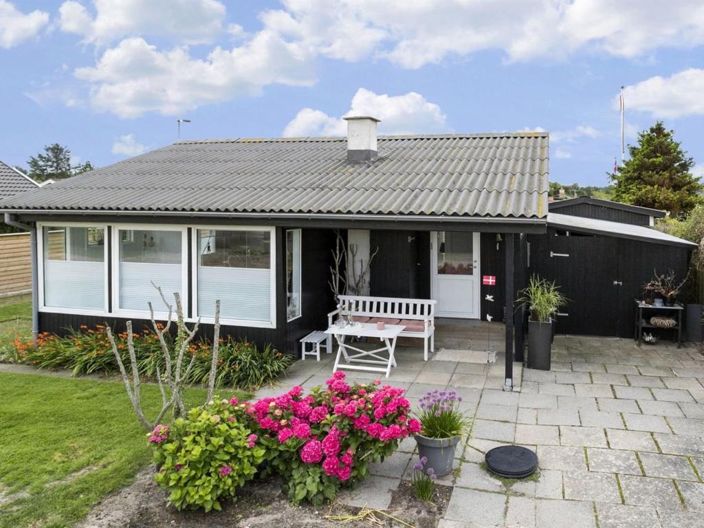 a house with a bench on a patio with flowers at Holiday Home Elisabeta - 60m from the sea in SE Jutland by Interhome in Juelsminde