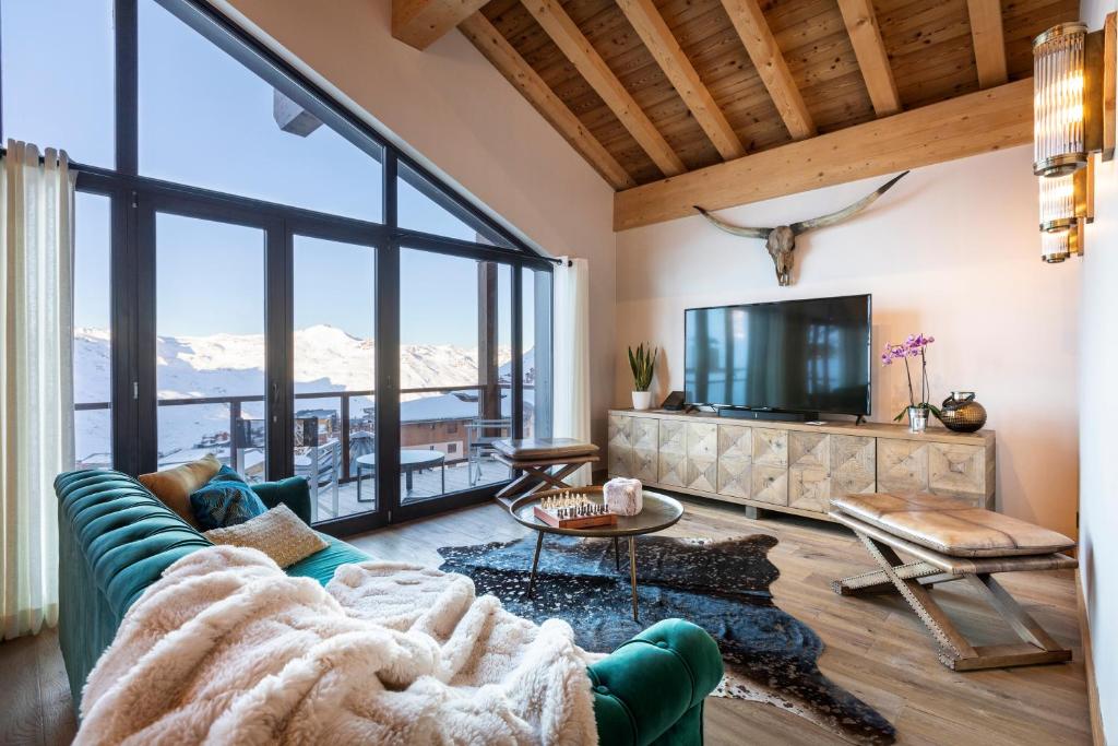 a living room with a couch and a tv at Chalet Carte Blanche Golden Jubilée in Val Thorens