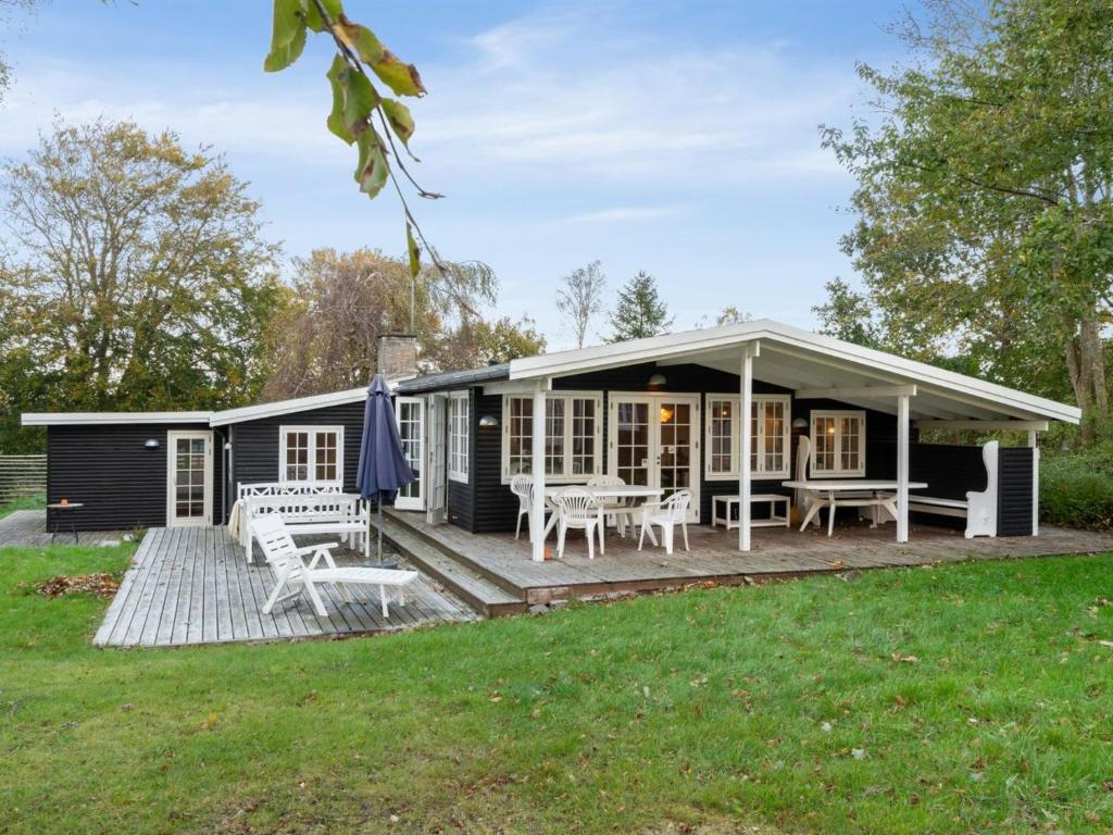 ein schwarzes Cottage mit Tischen und Stühlen auf einer Terrasse in der Unterkunft Holiday Home Rami - 2km from the sea in Sealand by Interhome in Tisvildeleje